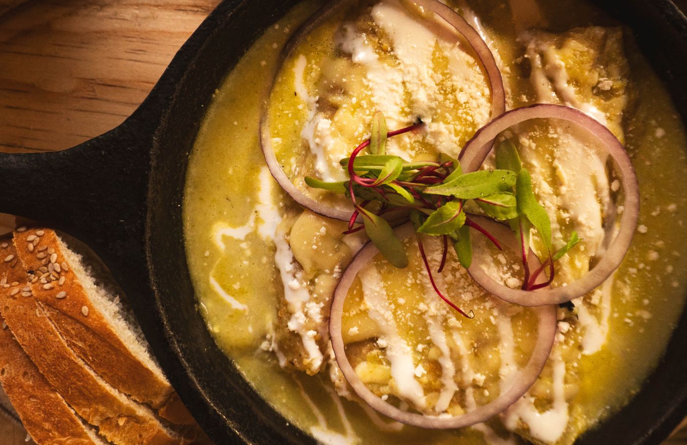 Enchiladas topped with green sauce, crema and queso fresco